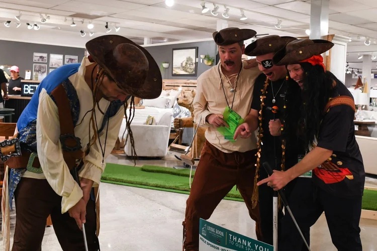 A team in pirate costumes lining up a putt on the showroom floor at the 2025 tournament
